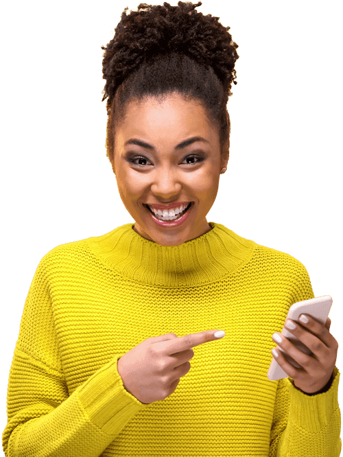 A smiling woman in a bright yellow sweater pointing to her mobile phone.